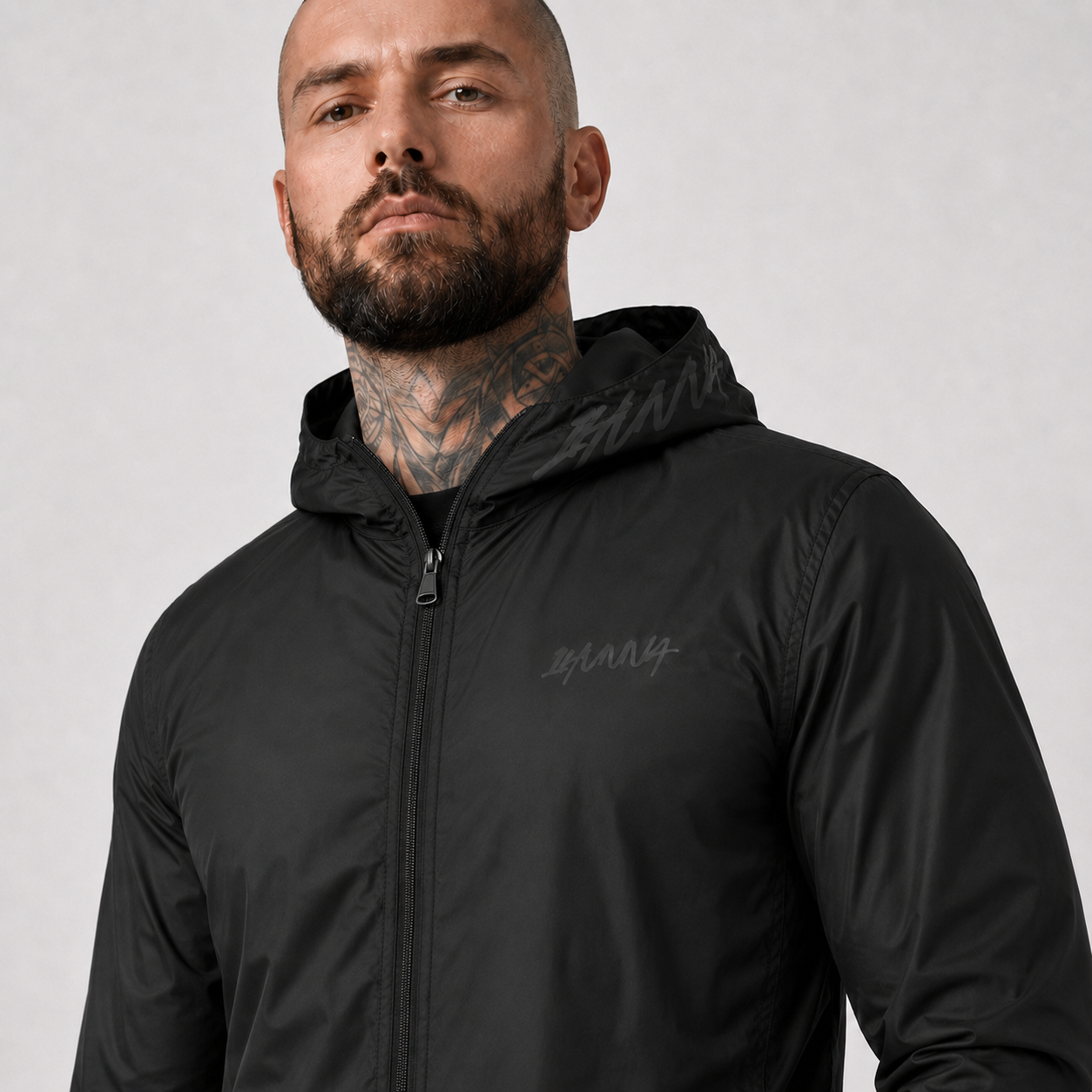 Detail van de zwarte 1HUNNA Ghost Windbreaker met borstlogo en capuchon